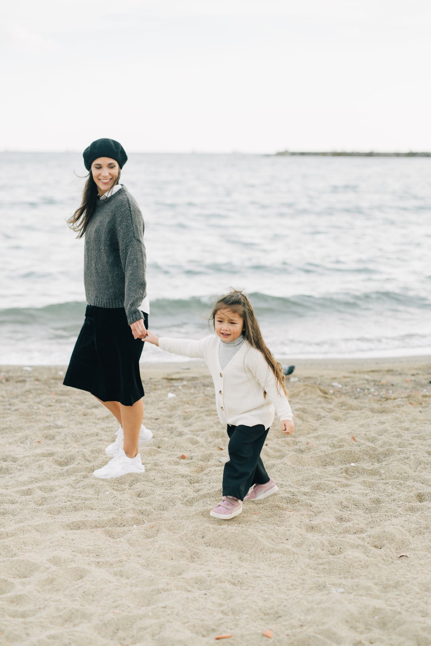A parent and child holding hands on a beach